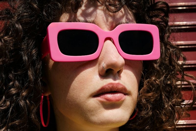 Femme aux cheveux bouclés en été portant des lunettes de soleil