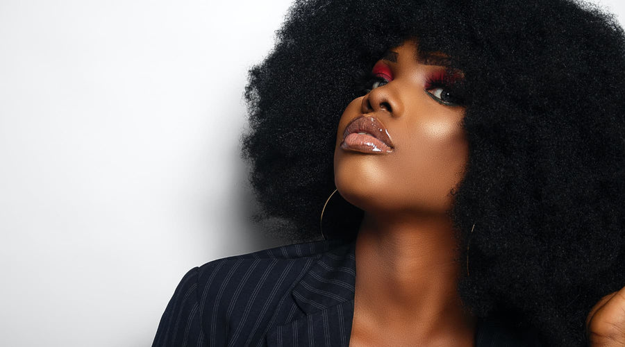 Femme noire peau ébène avec un afro volumineux et le cheveu crépu par Saison des Pluies marque du leave in conditionner pour cheveux crépus, cheveux bouclés, cheveux ondulés naturel à 97%. Spray sans rinçage 3 en 1