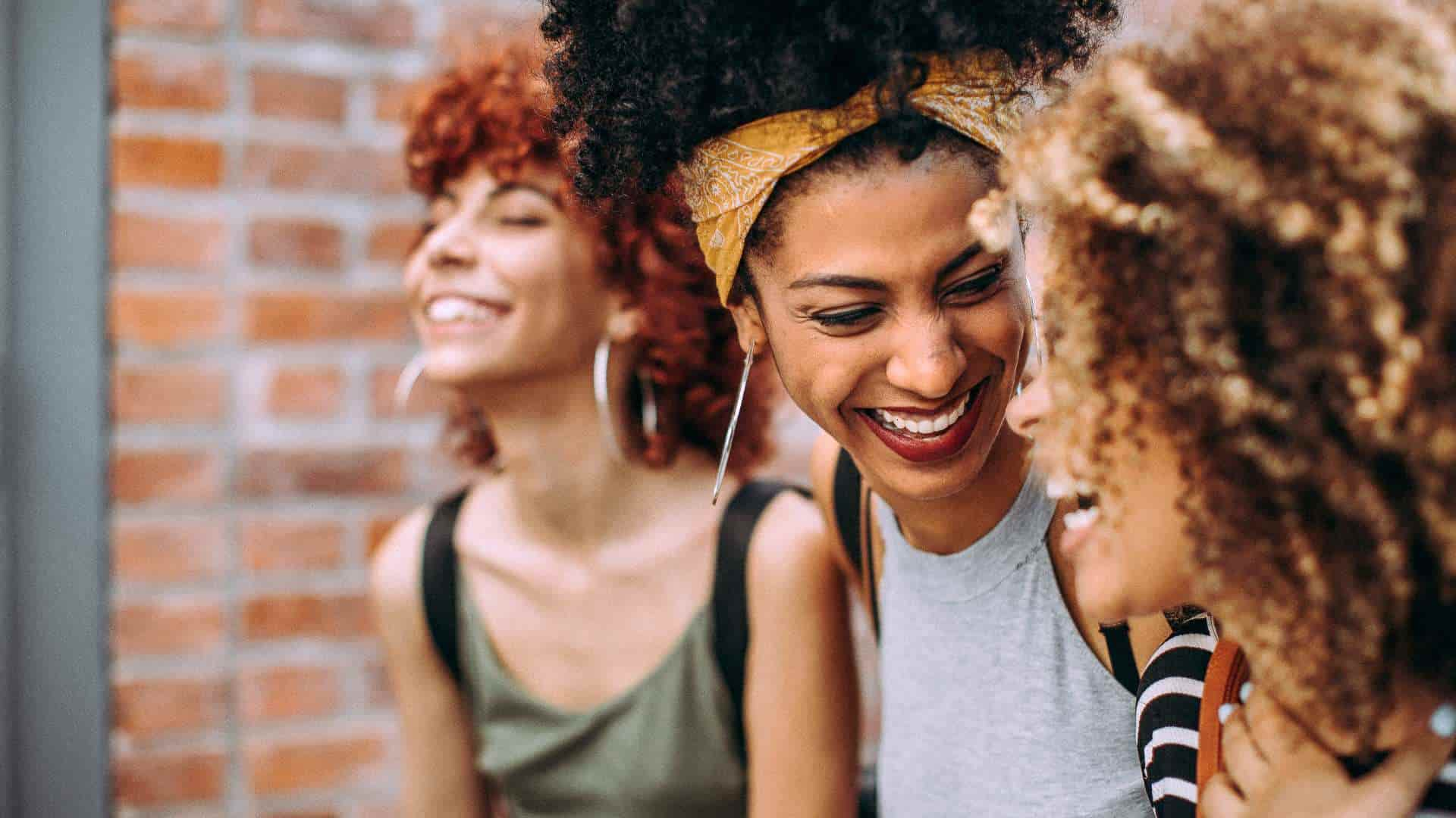 Trois femmes aux cheveux bouclés cheveux frisés cheveux ondulés sourient et marchent dans la rue