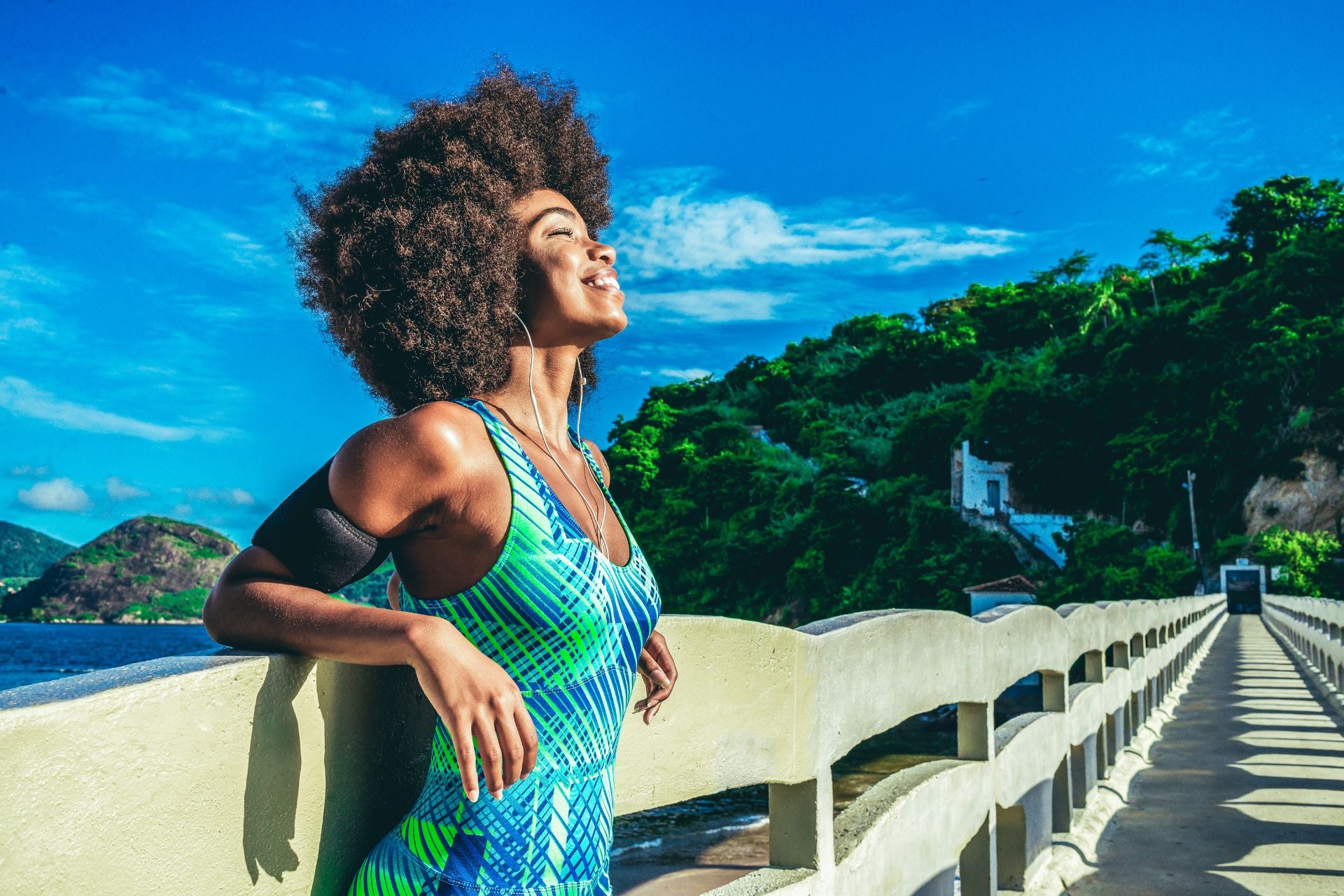jeune-femme-noire-avec un-afro-long-souriant-en-maillot-de-bain-bleu-sur-la-plage