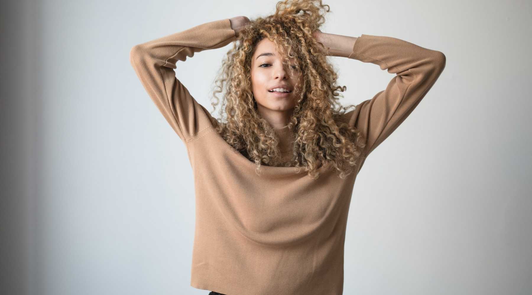 Femmes cheveux bouclés colorés portant un pull beige par Saison des Pluies marque du soin leave in conditionner So Wet Oh !