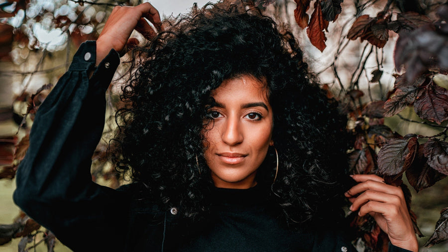 jeune-femme-aux-cheveux-bouclés-longs-et-noirs-se-passant-la-main-dans-ses-boucles