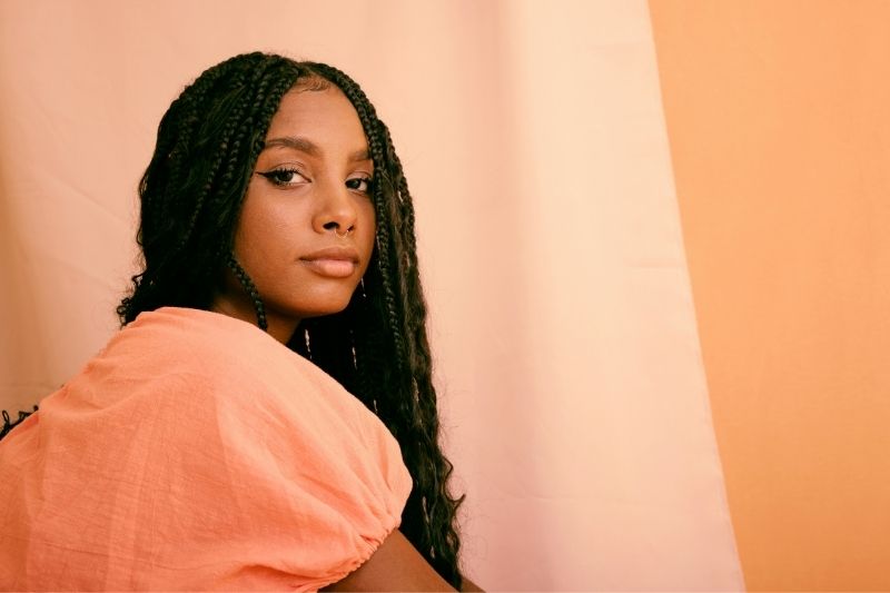 Femme portant des box braids longues, exemple de coiffure protectrice entretenue grâce à une hydratation légère.