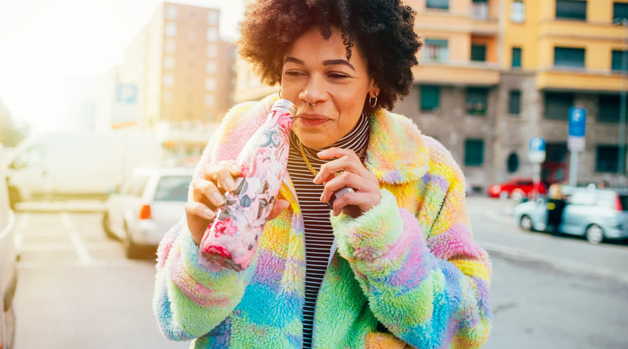 femme métisse aux cheveux crépus qui tient une gourde d'eau saison des pluies