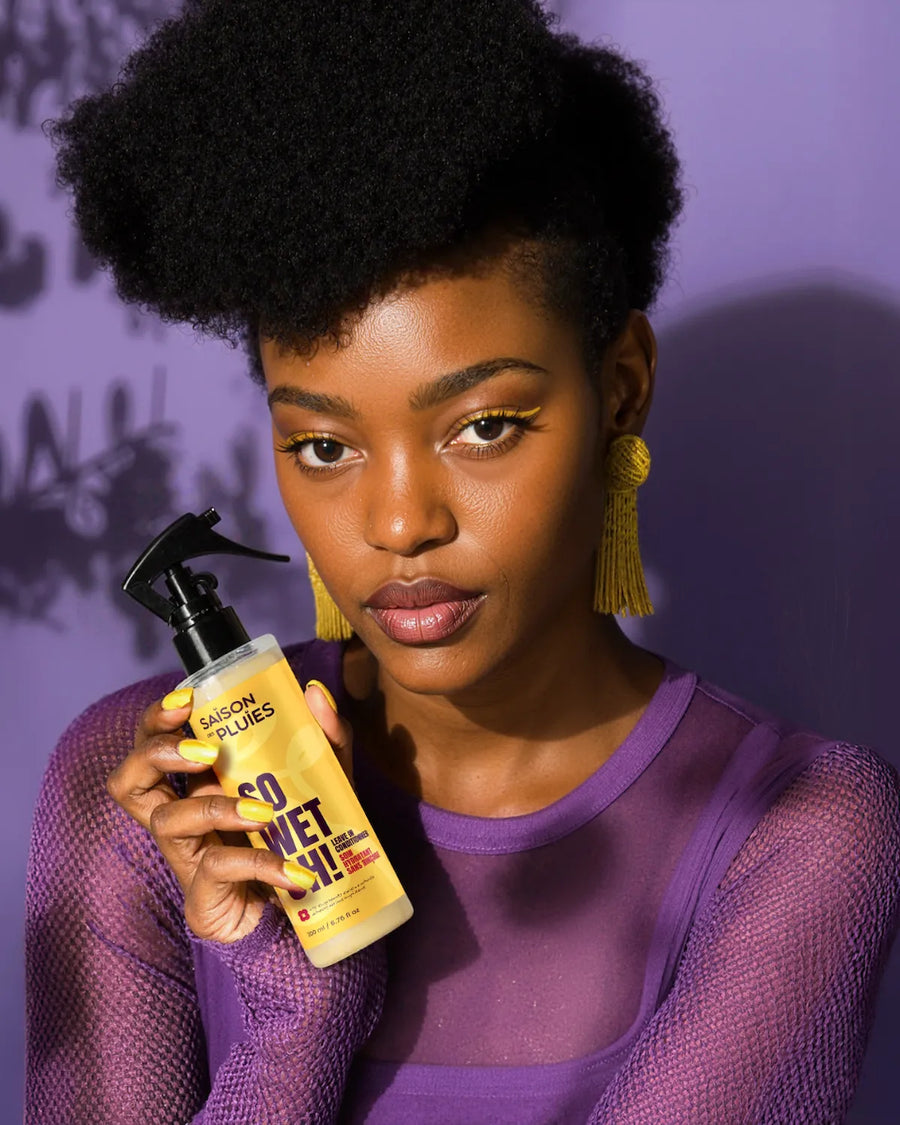 Femme aux cheveux afro tenant spray hydratant sans rinçage so wet oh pour cheveu sec
