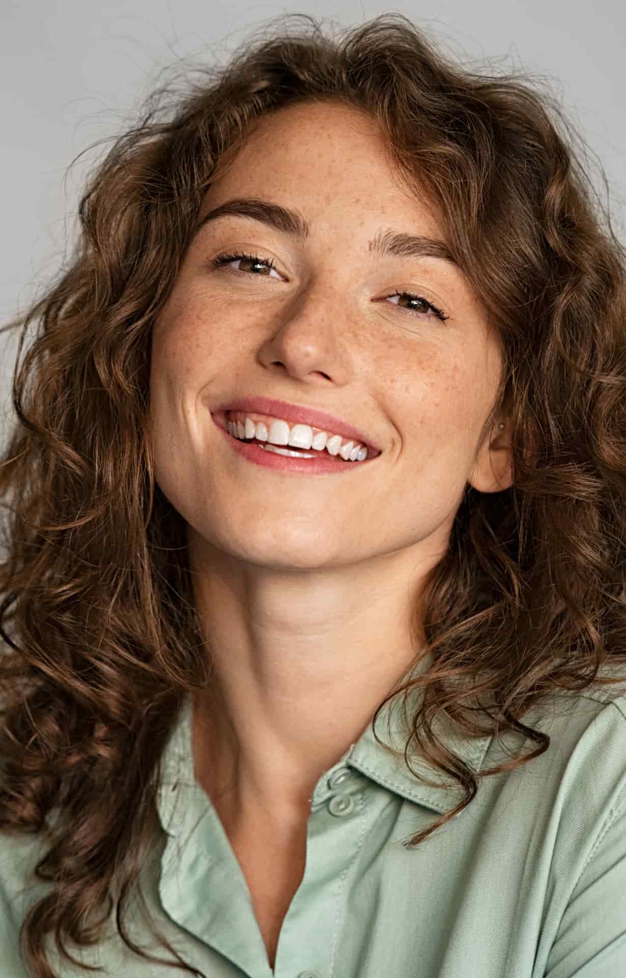 Portrait femme aux cheveux ondulés qui sourit par saison des pluies marque de soins hydratant naturels